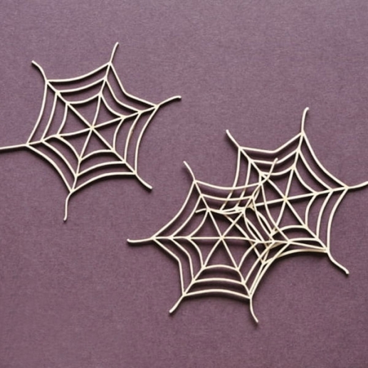 Tre vita chipboardutskärningar formade som spindelnät, 6x6 cm.